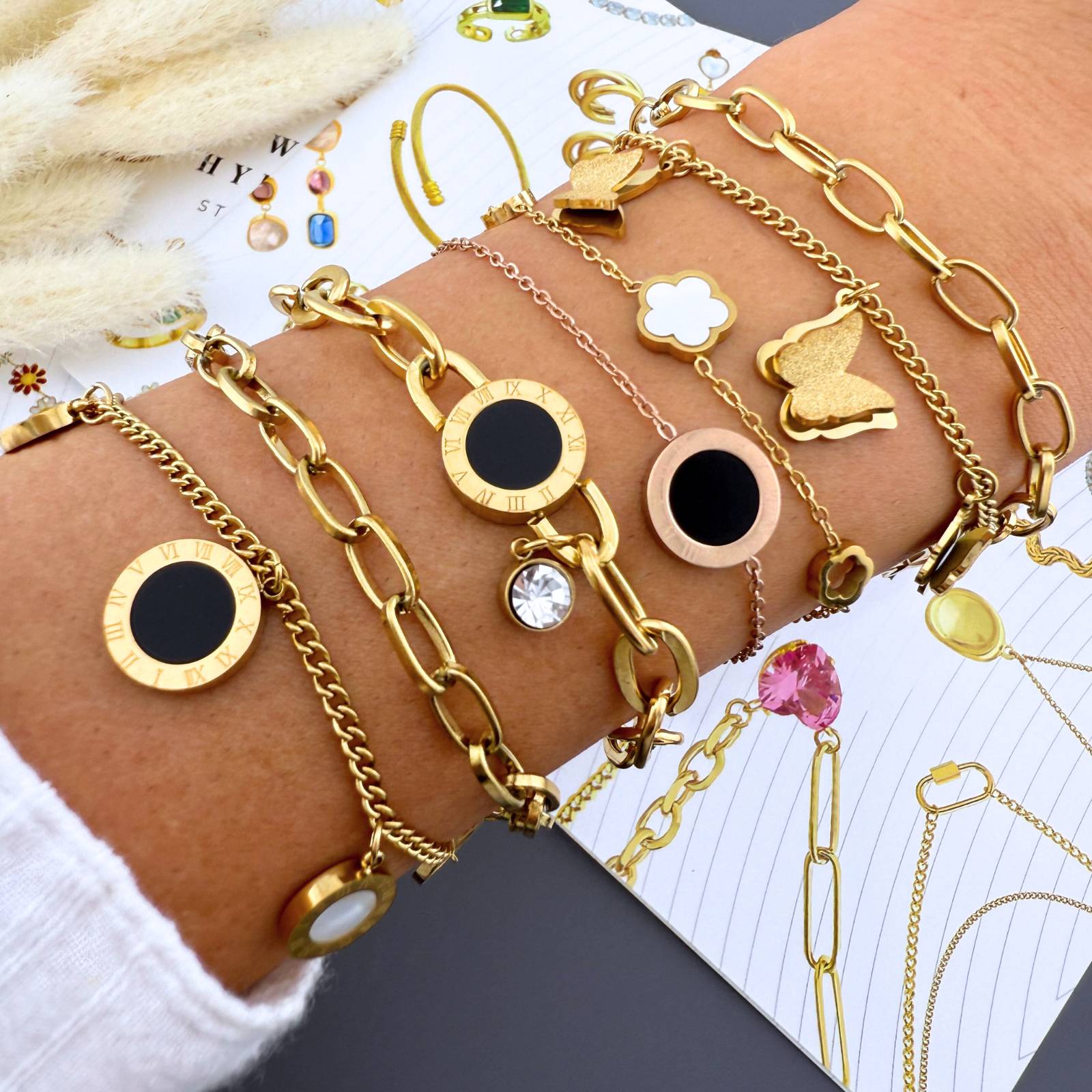 Bracelet de charme en acier inoxydable plaqué or 18K, orné de pendentifs disques aux chiffres romains. Son design à chaînes superposées offre une élégance intemporelle. Ajustable de 16cm à 21cm, il s'adapte à tous les poignets. Résistant à l'eau.
