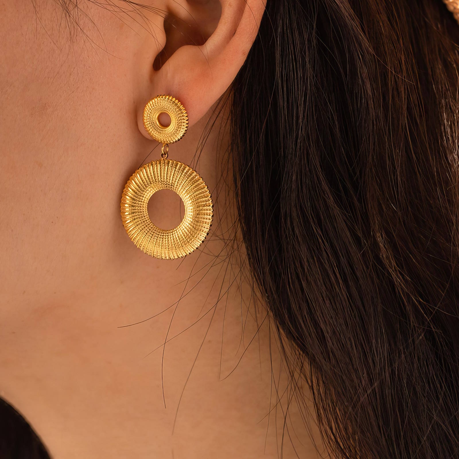 Boucles d'oreilles en acier inoxydable plaqué or 18K, design double cercle ajouré avec finition texturée. Fermeture à tige. Dimensions : 4,3 x 2,5 cm.